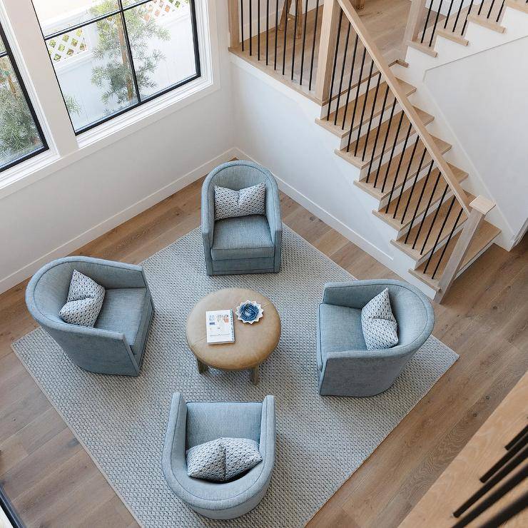 Blue swivel chairs placed on a blue lattice rug sit around a round brown leather ottoman.