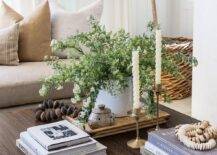 A dark brown styled coffee table is accented with stacked coffee table books and vintage brass candle holders.