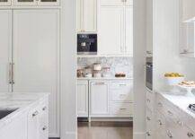 Colorful kitchen runner leads to a butler's pantry with a transom window and white cabinets with nickel pulls.