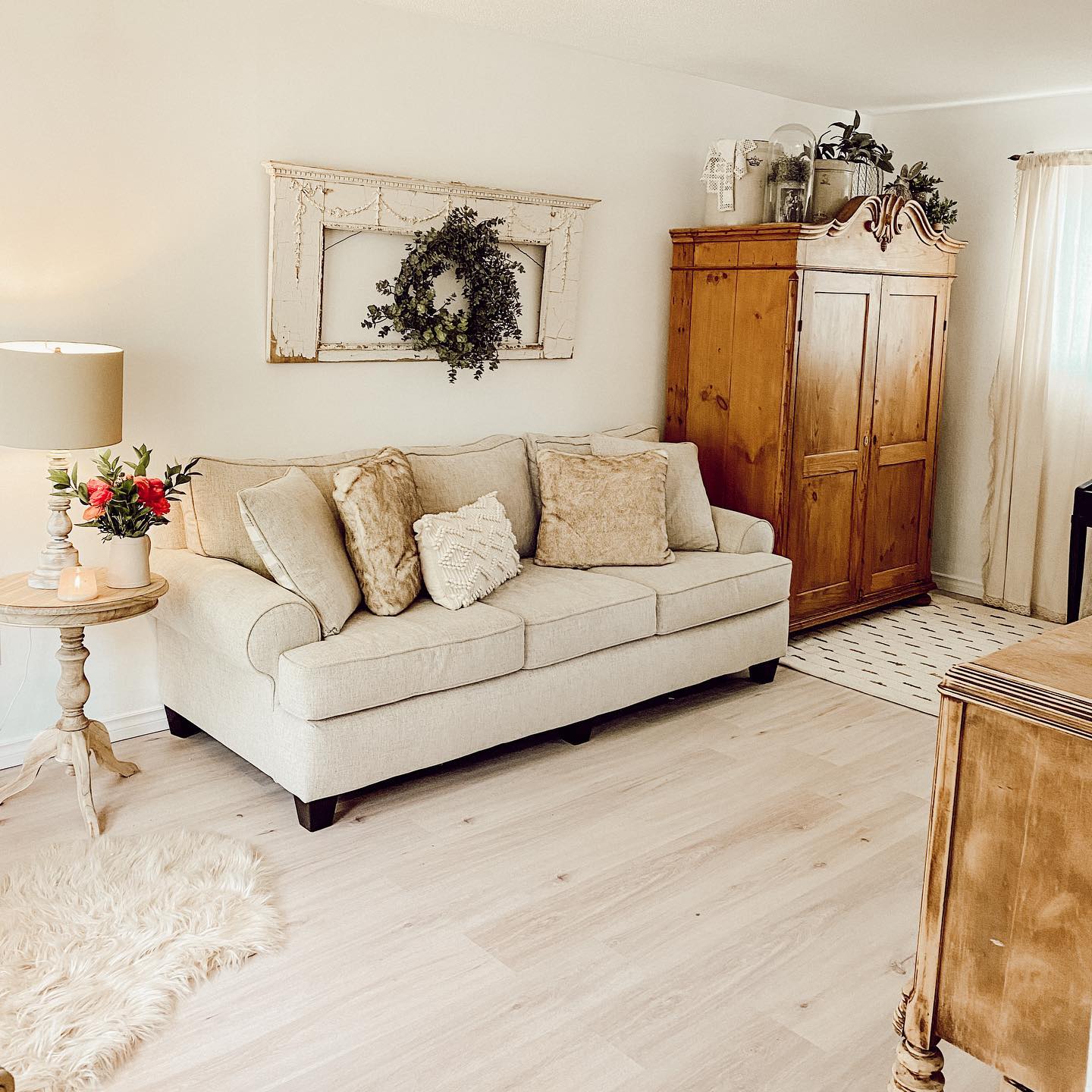 white living room with wood antique wardrobe throw pillows wreath hanging on architecture