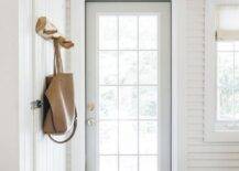 A blue vintage rug sits in an entryway beneath a blond plank ceiling and in front of a dove gray front door finished with 15 glass panels.