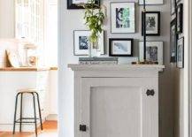 Aerin Charlton Lamp adorns a white painted vintage foyer cabinet styled with a black and white photo gallery wall in a small foyer space.