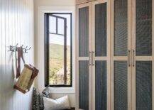 Cabin styled angled mudroom features mesh lockers, a small built in window bench and herringbone floors.