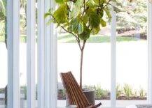 Sunroom as a bedroom features an oak plank ceiling, a wooden accent chair and a small white pedestal accent table.