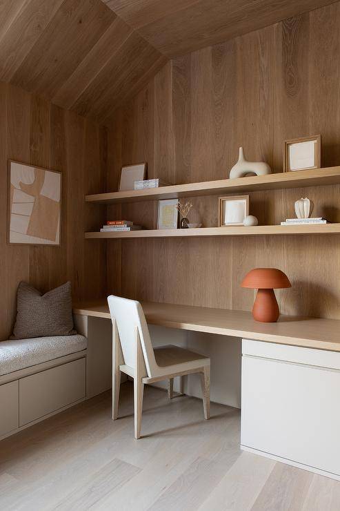 A wood and leather chair sits at a built in wooden desk illuminated by a terracotta mushroom lamp.