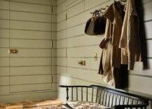 Green shiplap mudroom features a jib door and a black vintage bench on terracotta hexagon pavers.