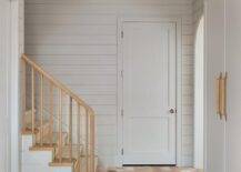 Terracotta hexagon pavers accent a mudroom boasting light light gray built-in cabinets accented with wood and leather pulls.