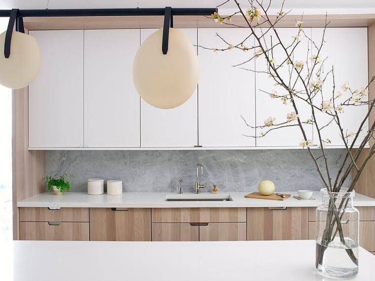 Modern tan oak kitchen cabinets paired with gray marble in a modern kitchen designed with white upper cabinets creating a two-tone appeal.