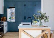 Two-toned kitchen featuring a blond x wood trim shiplap island with backless french bistro counter stools, white quartz countertops and a matte black faucet.