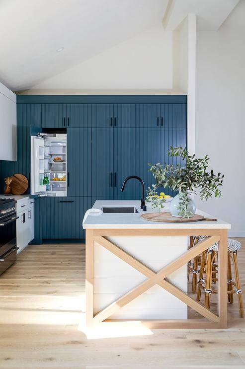 Two-toned kitchen featuring a blond x wood trim shiplap island with backless french bistro counter stools, white quartz countertops and a matte black faucet.