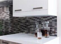 Fantastic two-tone kitchen boasts white flat front upper cabinets and brown oak veneer bottom cabinets adorned with nickel pulls paired with white quartz countertops and a silver and gray mosaic tile backsplash.