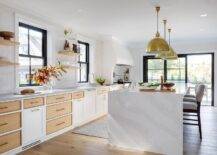 Heather gray counter stools sit at a marble-look waterfall edge top island illuminated by Eugene Pendants.