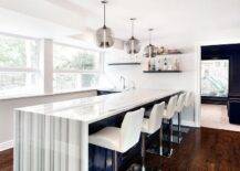 Smoke gray glass light pendants illuminate a modern blue kitchen island with a gray striped marble waterfall countertop and white swivel island stools.