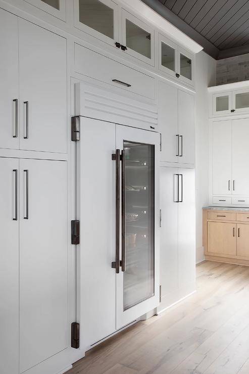 Black and white kitchen features a white modern fridge with a clear glass door and white cabinetry.