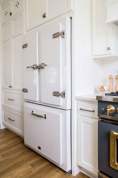 Kitchen features a white vintage refridgerator with satin nickel vintage latches surrounded by white cabinetry.