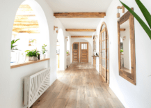 A bright white hallway with mirror on the wall.