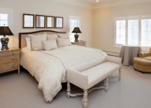 Large white bed in a master bedroom with pictures hung overhead.