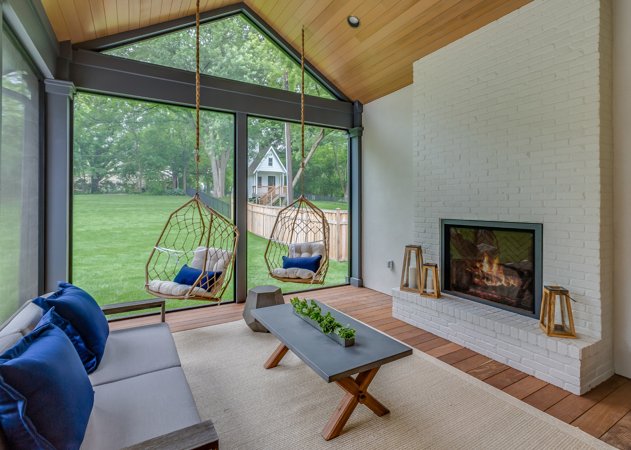 small sunroom with brick fireplace and hanging chairs